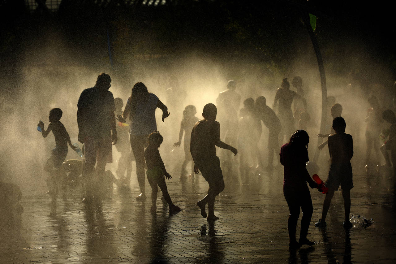 Folk kjøler seg ned i vannet i parken Madrid Río i Spanias hovedstad. Foto: AP / NTB scanpix