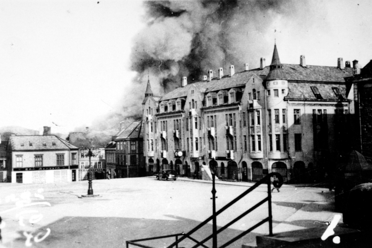 Datoen er 28. april 1940, og Sparebanken i Storgata 2 brenner etter å ha blitt bombet av tyske bombefly. Foto: Stiftelsen Nordmøre Museum.