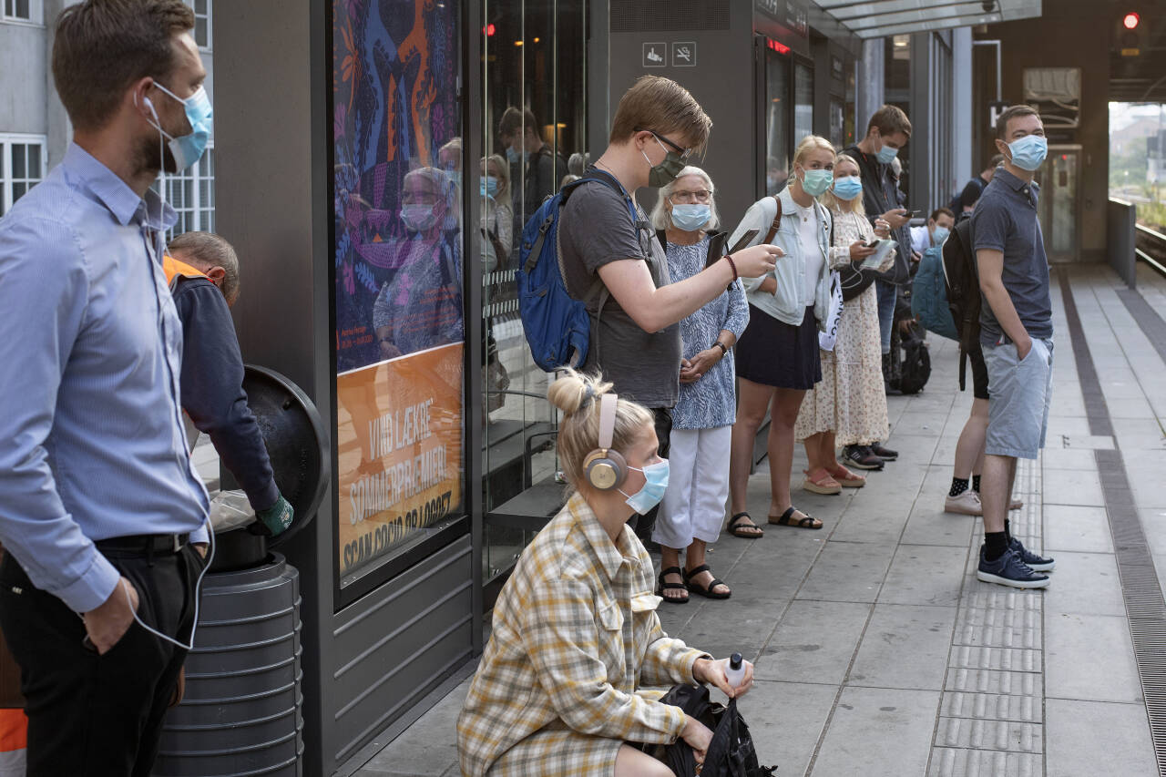 Passasjerer med munnbind venter på toget i Aarhus. Dette bildet ble tatt tidligere i august, da det bare var gitt råd om munnbindbruk. Lørdag ble det et krav. Foto: Bo Amstrup/Ritzau Scanpix via AP/NTB scanpix
