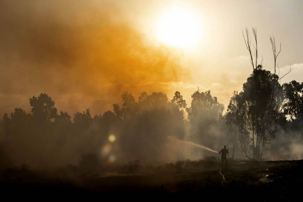 Israelske arbeidere arbeider med å slukke en brann som oppsto da en av flere raketter ble skutt mot Israel natt til fredag. Foto: Tsafrir Abayov / NTB scanpix