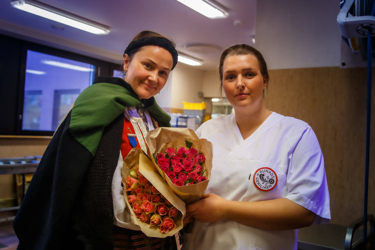 Kokk Madelen Ohrvik (til høyre) på sykehuskjøkkenet ved Kristiansund Sykehus, overrekkes blomster av leder i Bunadsgeriljaen, Anja Solvik (til venstre). Foto: Steinar Melby / KSU.NO