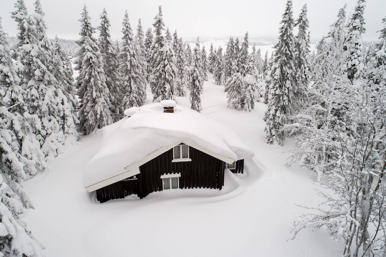 Dette bildet er fra en tidligere vinter. Men tung og våt snø venter de som skal tilbringe vinterferien på Sjusjøen i år. Hytteeiere bør vurdere hvor mye taket tåler. Foto: Tore Meek / NTB scanpix