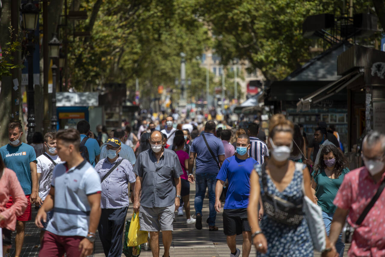 Innbyggere med munnbind går nedover hovedgata La Rambla i Barcelona torsdag.Foto: Emilio Morenatti/AP Photo/NTB scanpix