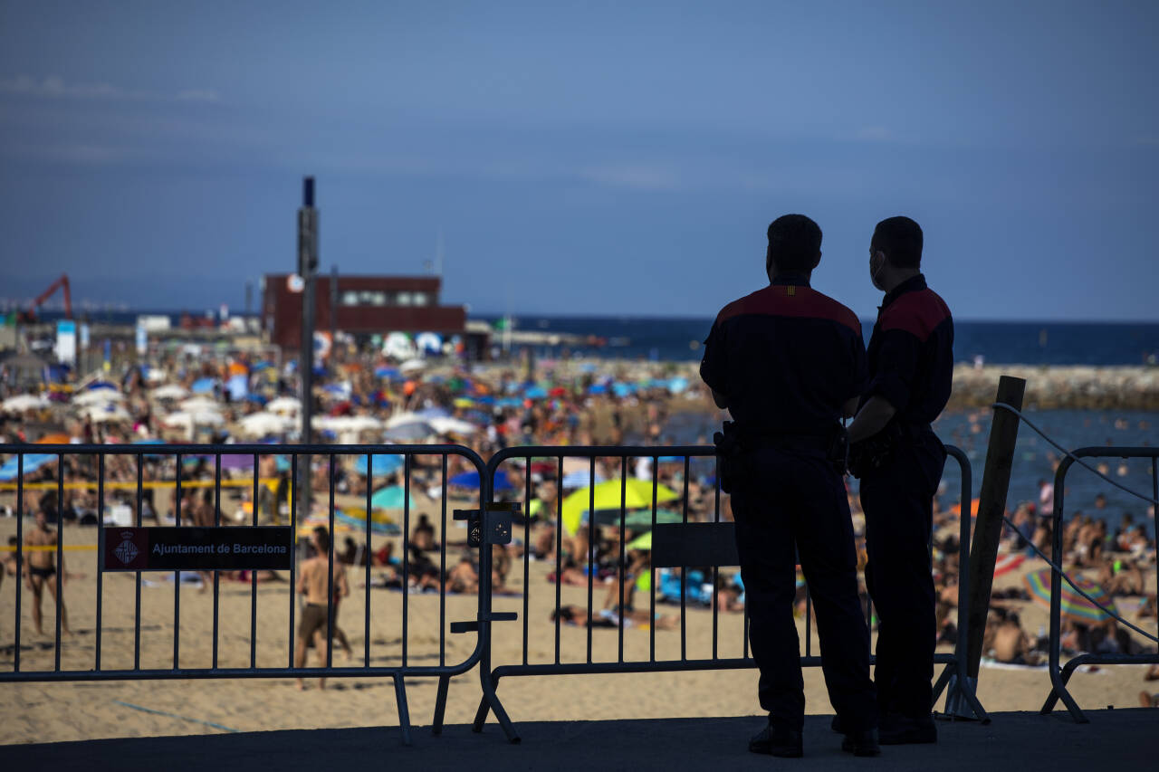 Politiet passer på at ikke flere personer bruker stranden i Barcelona. Til tross for at antallet tilfeller av korona i Nord-Spania øker, er det mange som ikke forholder seg til smittebegrensningstiltakene. Foto: Emilio Morenatti / AP / NTB scanpix