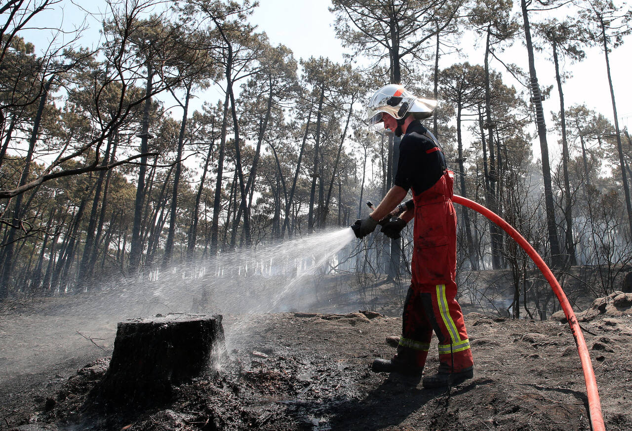 En brannmann jobber med å slukke fredagens brann i Chiberta-skogen i Angelet, i det sørvestlige Frankrike. Mer enn 100 hektar med skog og rundt ti hus brant ned. Foto: Bob Edme / AP / NTB scanpix
