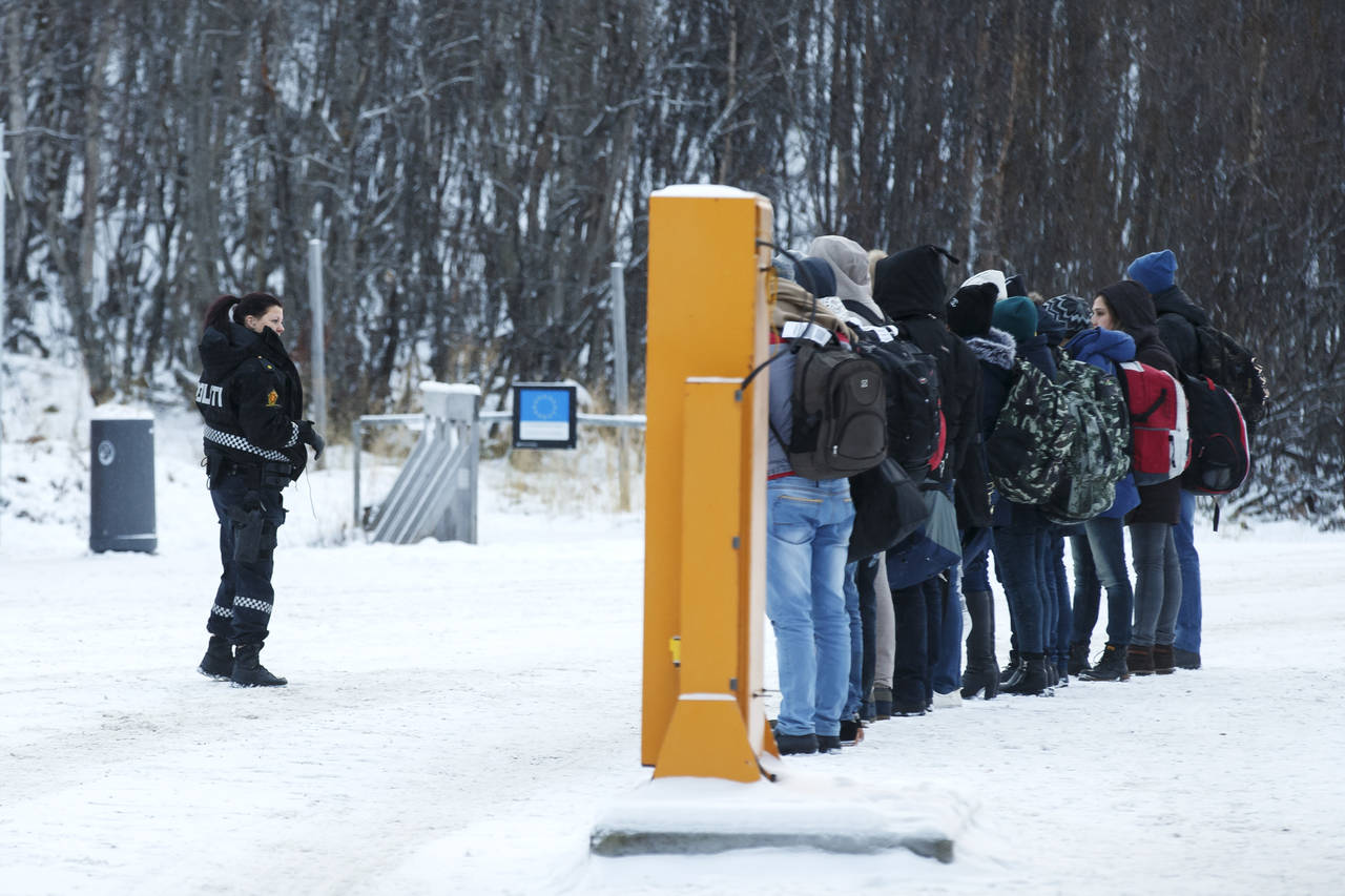 En norsk politikvinne sammen en gruppe asylsøkere på Storskog grensestasjon på den norsk-russiske grensen i november 2015. Foto: Cornelius Poppe / NTB scanpix