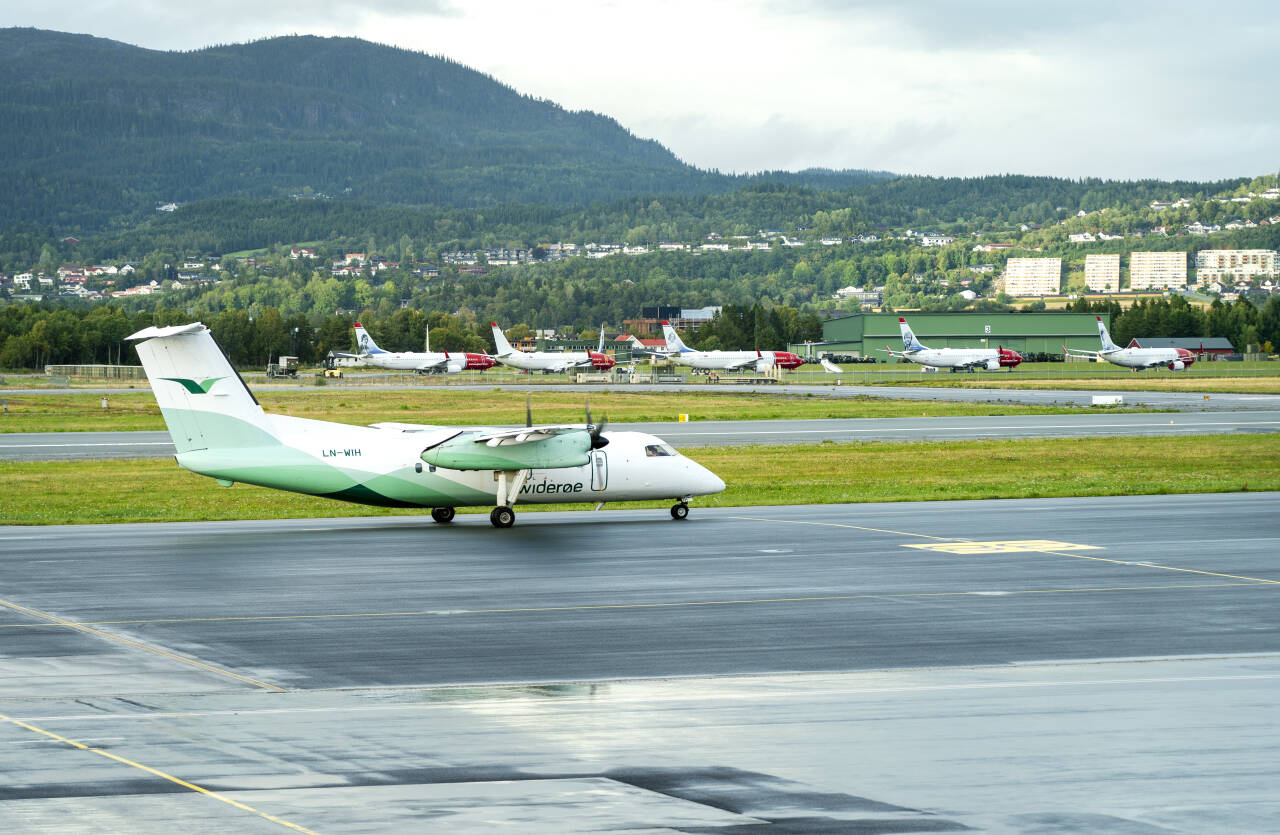 Et Widerøe-fly tar av fra Trondheim lufthavn tidligere i år. I bakgrunnen står flere av flyene som Norwegian har satt på bakken. Foto: Gorm Kallestad / NTB