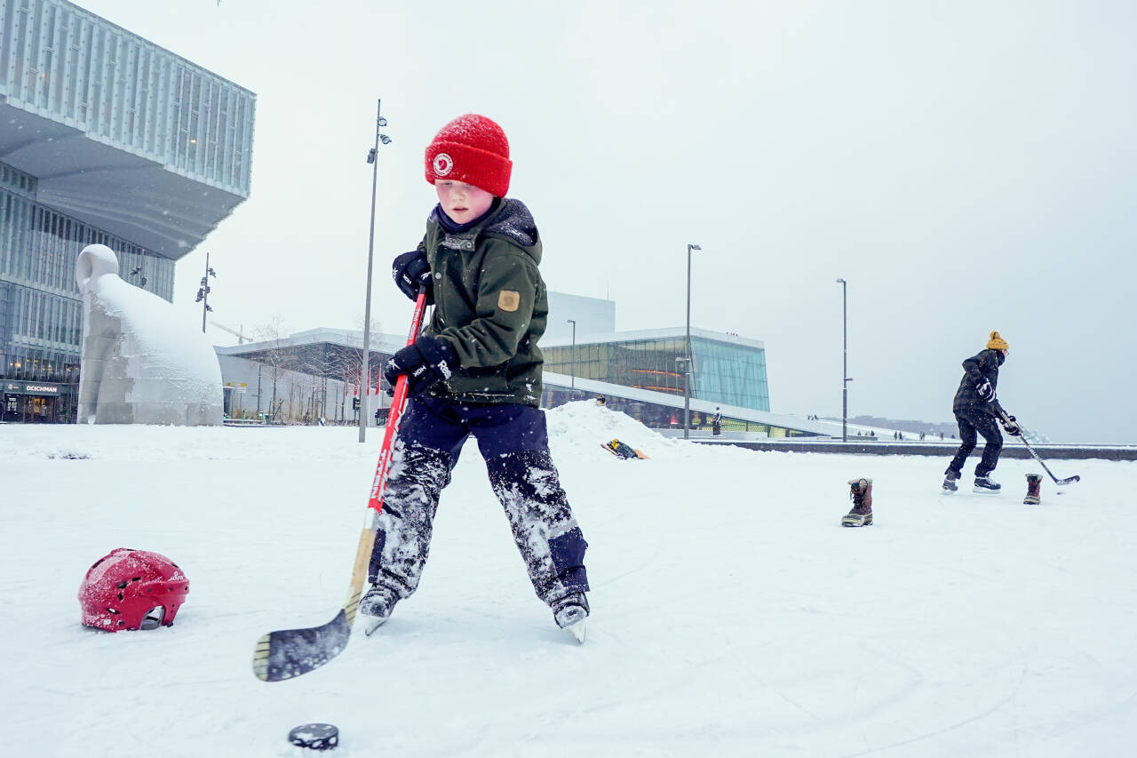 Ingen Tromsø-mengder å skryte av i hovedstaden når det gjelder snø. Men skøyteisen er OK! Frans (8 år) og pappa Marius Stubberud fra Vålerenga spiller ishockey utenfor Deichman bibliotek og Operaen i Oslo sentrum.Foto: Lise Åserud / NTB