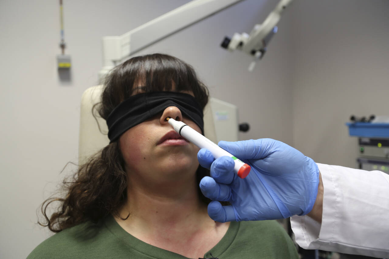 Doktor Clair Vandersteen holder en lukttube under nesen til Gabriella Forgione, som har slitt med tap av lukte- og smakssansen siden hun ble koronasyk i november. Foto: John Leicester / AP / NTB