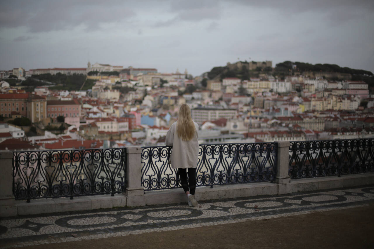 En kvinne ser utover Lisboa i Portugal. Landet har de siste ukene hatt blant verdens høyeste smitte- og dødstall, men nå stiger håpet om at det verste kan være over. Foto: Armando Franca / AP / NTB