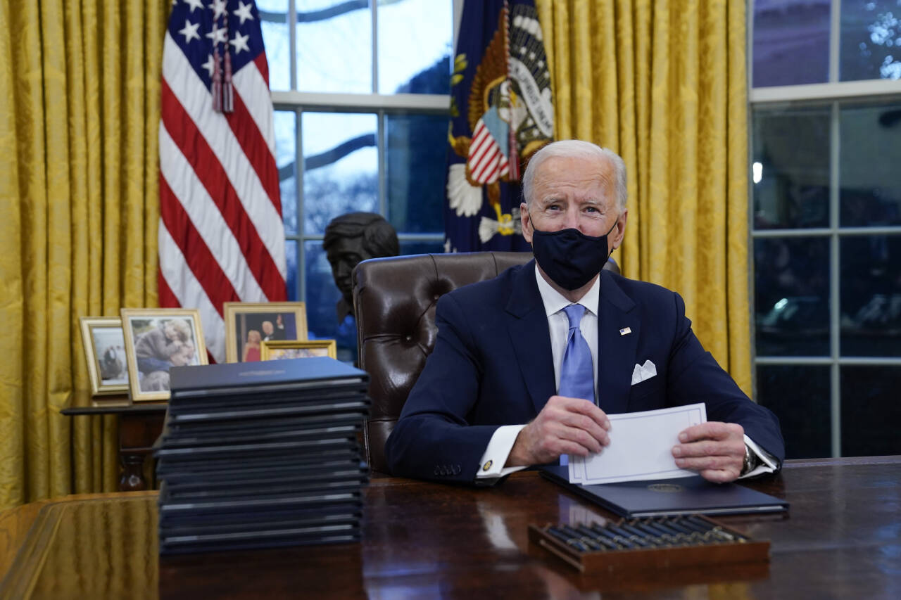 President Joe Biden undertegner sine første presidentordrer i Det ovale kontor, blant annet om å melde USA inn igjen i Paris-avtalen. Foto: Evan Vucci / AP / NTB