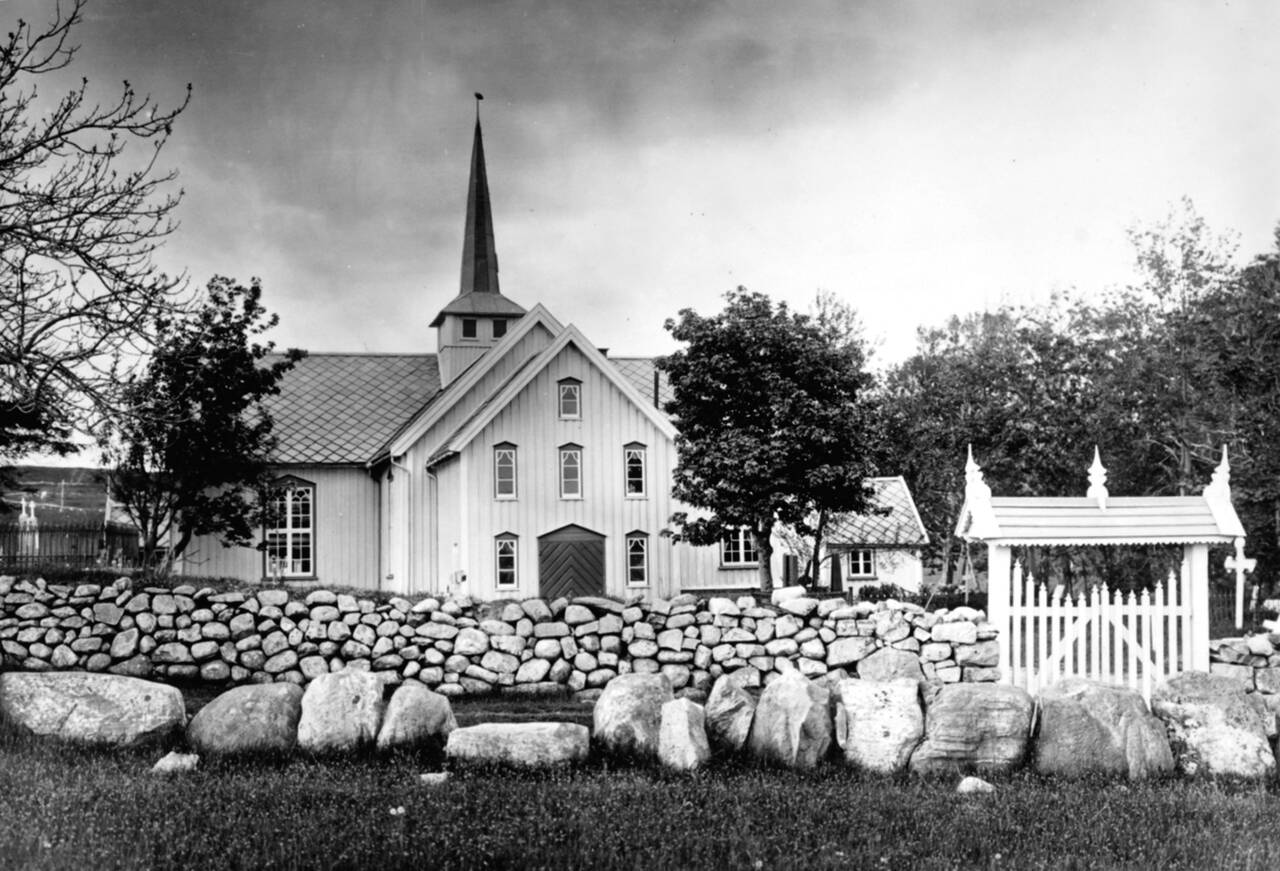 Et gammelt bilde av Bremsnes kirke med den eldste kirkegårdsporten. Den var av tre med overbygg tekket med trespon. Bilde fra Nordmøre museum