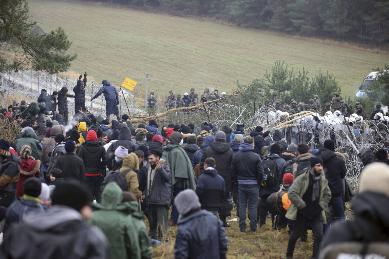 Migranter fra Midtøsten forsøker å komme seg over grensen, men blir stanset av polske styrker. Foto: Leonid Shcheglov/BelTA via AP/NTB
