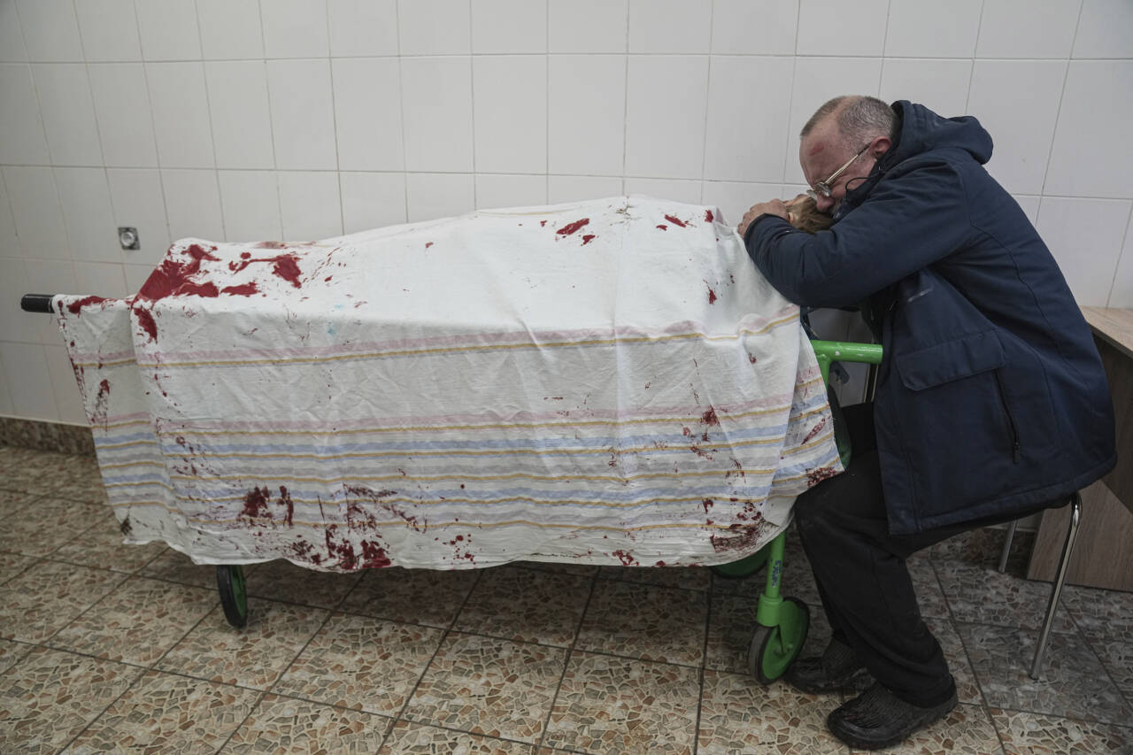 Serhij gråter ved det tildekkede liket av sønnen Ilija i Mariupol. Foto: Jevgenij Maloletka / AP / NTB