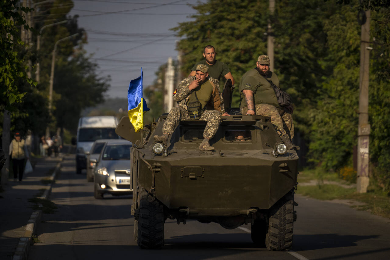 Ukrainske soldater kjører gjennom Butsja ved Kyiv. Foto: Emilio Morenatti / AP / NTB