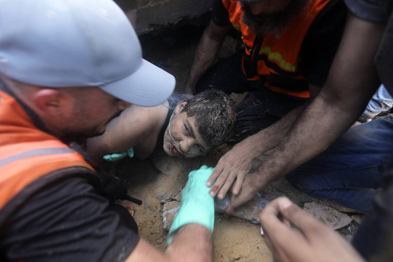 Palestinere forsøker å redde en gutt ut fra ruinene av en bombet bygning i Khan Younis sør på Gazastripen. Foto: Mohammed Dahman / AP / NTB