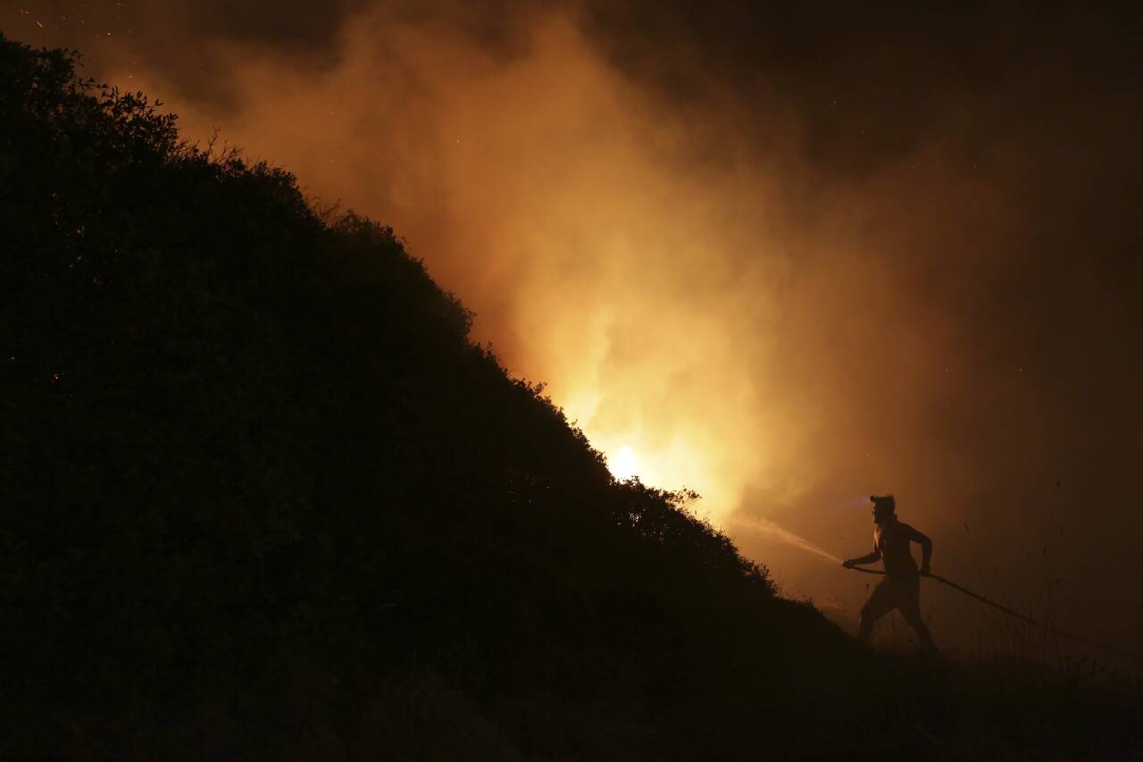 Klimaendringene har bidratt til å øke skogbrannfaren en rekke steder i verden. Bildet viser en frivillig i ferd med å slukke en brann i utkanten av Obidos i Portugal i 2017. Flere enn hundre mennesker omkom i skogbranner i landet dette året. Foto: Armando Franca / AP / NTB