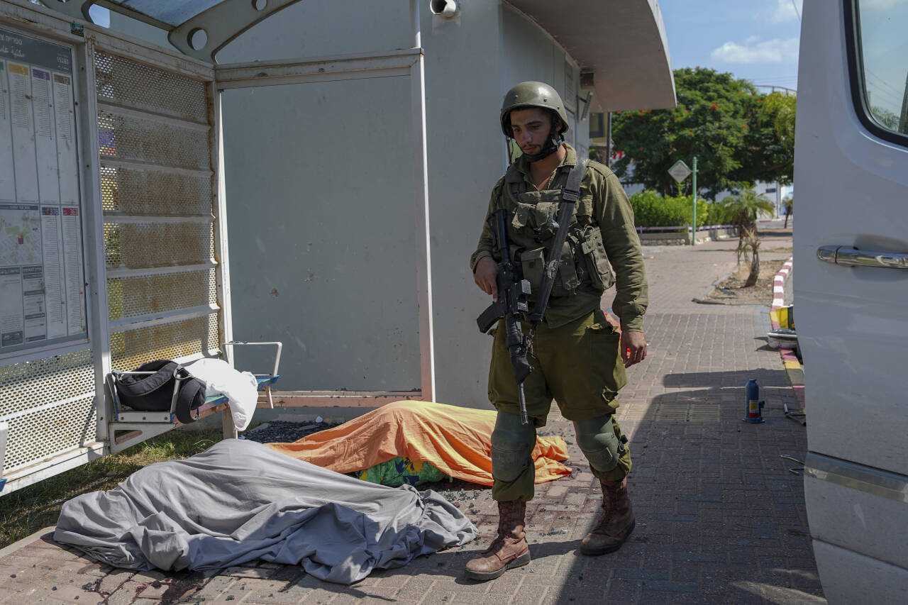 Hamas-angrepene på sivile fremstår som klare krigsforbrytelser, mener folkerettsekspert. Her er en soldat ved likene av noen av de israelske ofrene i Sderot lørdag. Foto: Tsafrir Abayov / AP / NTB