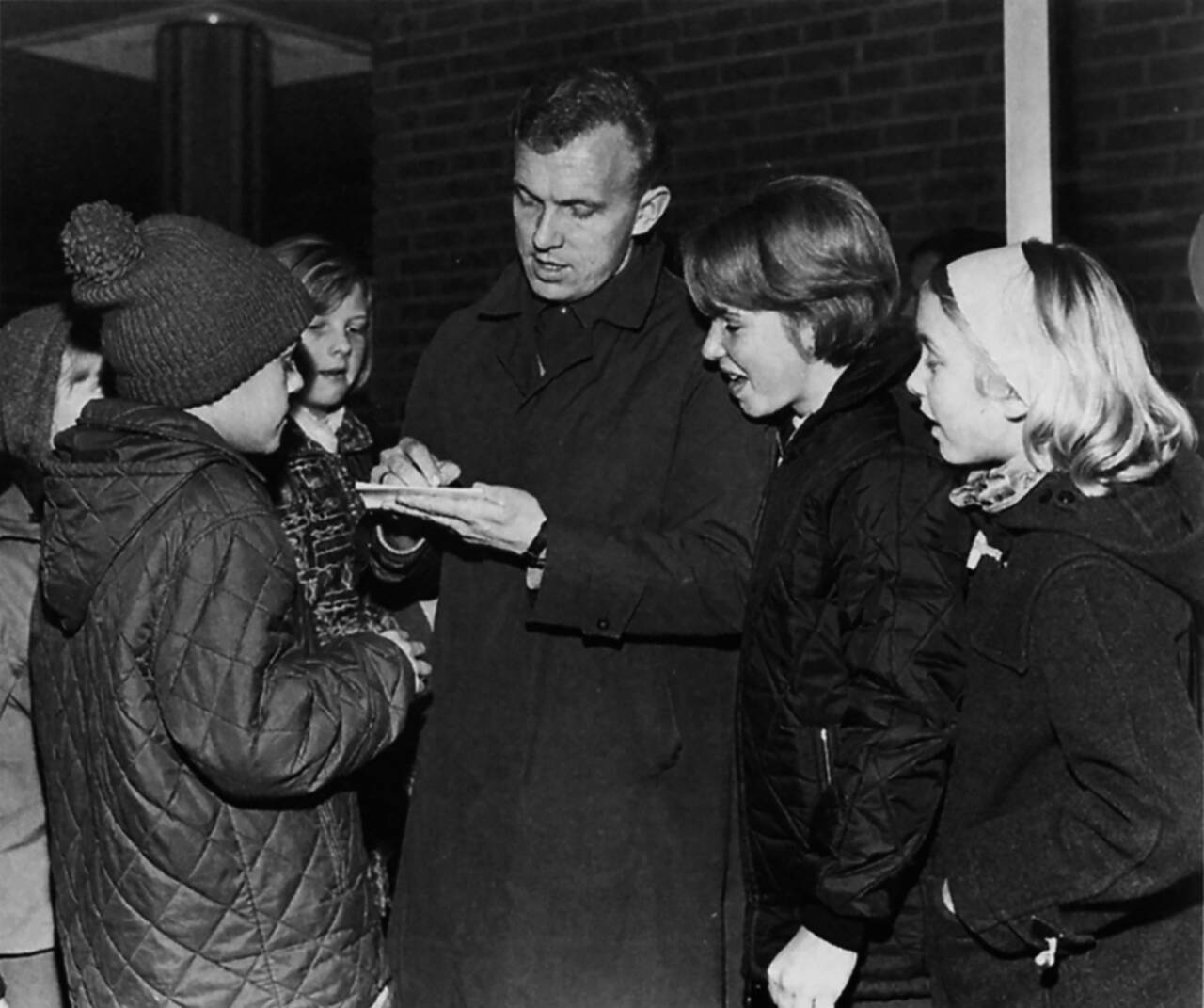 Ole Stavrum skriver autografer etter en landskamp i 1964. (Nasjonalbiblioteket)