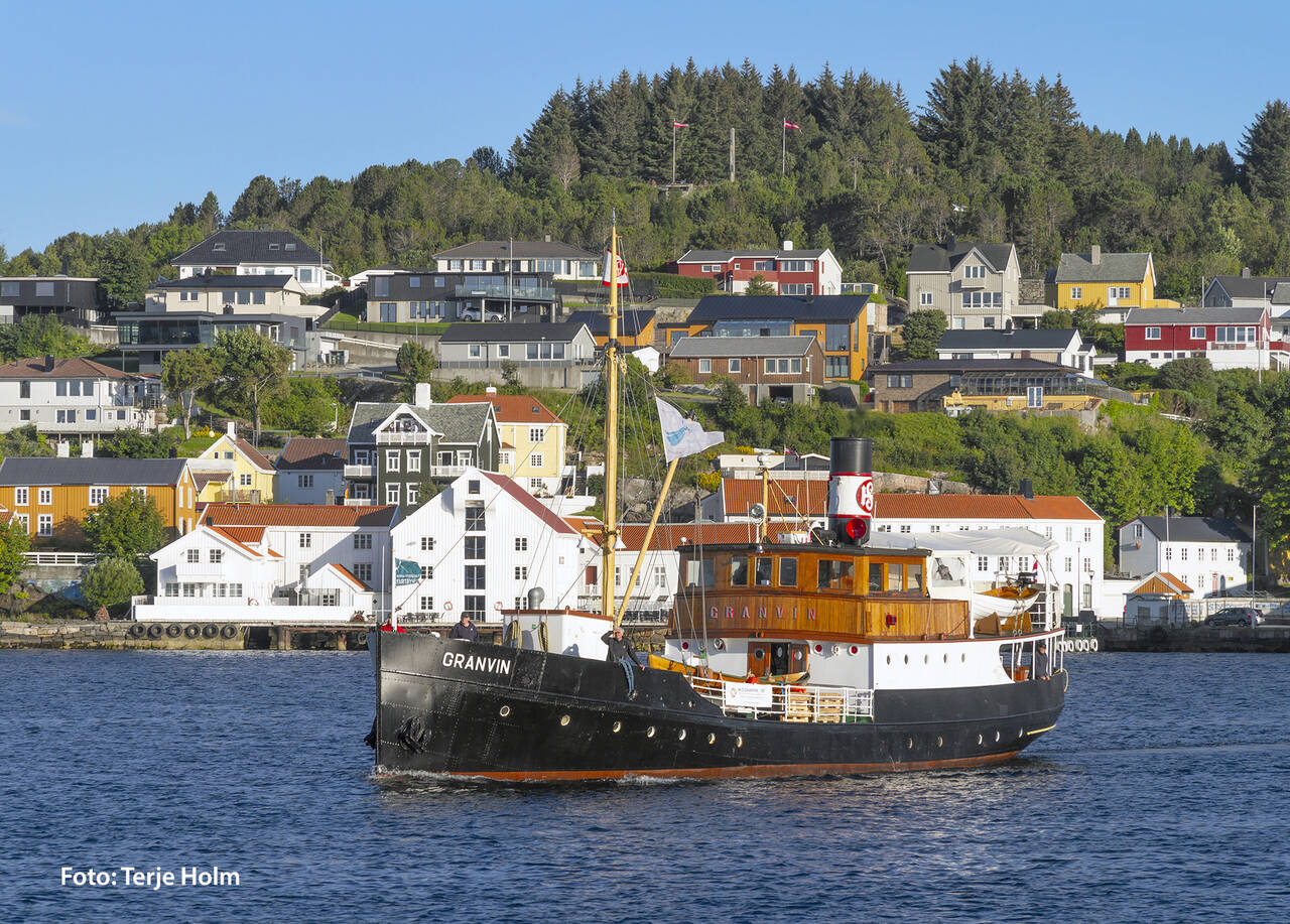 Det historiske lokalruteskipet «Granvin» fra 1931 med de historiske byggene på Innlandet i bakgrunnen. Foto: Terje Holm