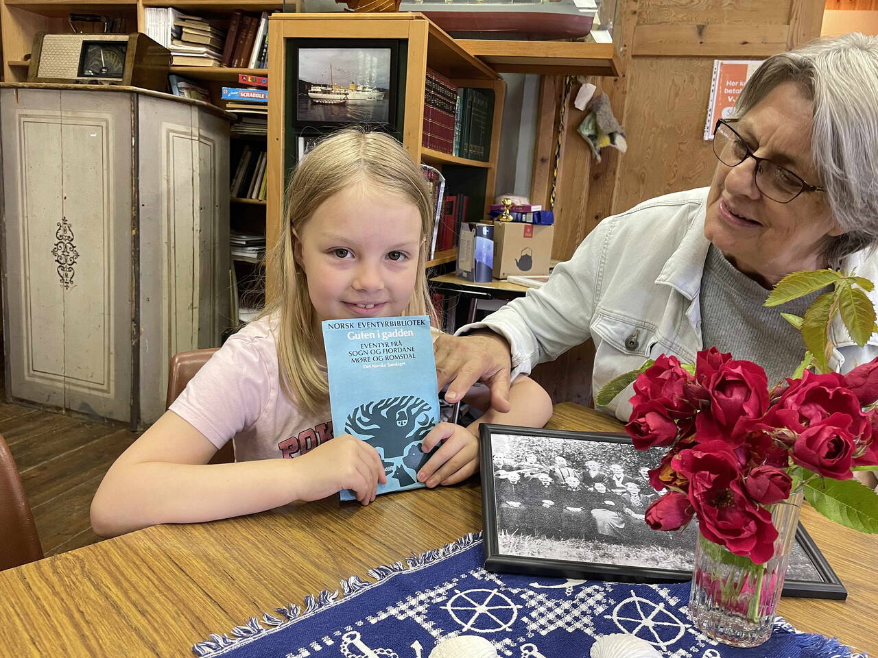 Augusta (7) og mormor Randi med samlinga «Guten i gadden». Namnet er etter eventyret frå Sollia og Dalabakken, som Maret Sollid skaffa plass i norsk eventyrlitteratur. (Maret kan skimtast i venstre kant på misjonsbiletet frå 1934.) Foto: Bernt Bøe