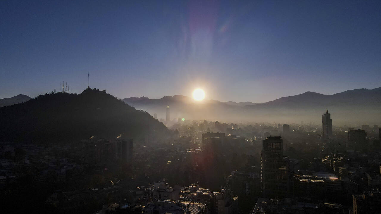 Solen reiser seg over Andesfjellene i Chile med Santiago i forgrunnen. En kraftig geomagnetisk storm er på vei mot jorda etter flere utbrudd fra en stor solflekk. Foto: Esteban Felix / AP / NTB