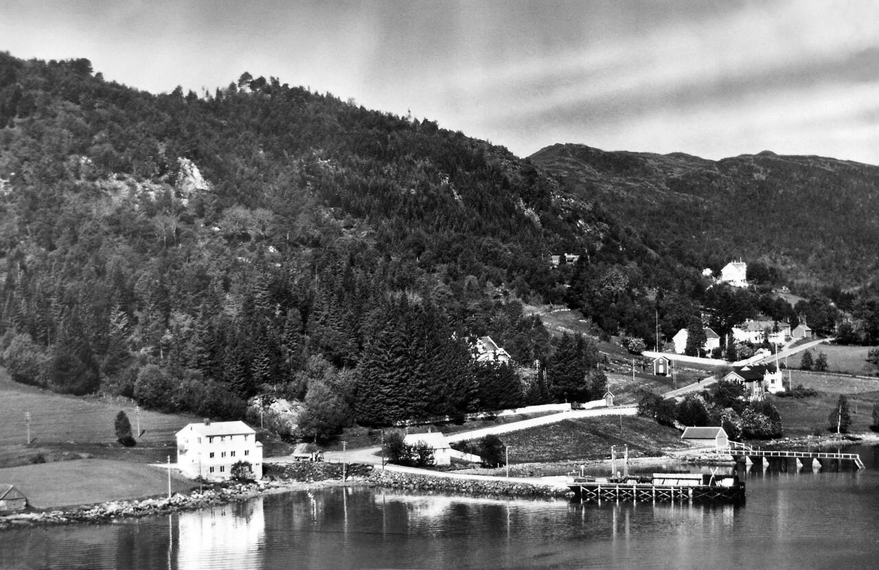 Kvernes med ferjekaia og samvirkelaget på 1950-tallet. Til høyre bak ferjekaia ser vi litt av landstedet til kjøpmann Jonas Eriksen. (Bilde fra boken Med kaffe og svele over fjorden)