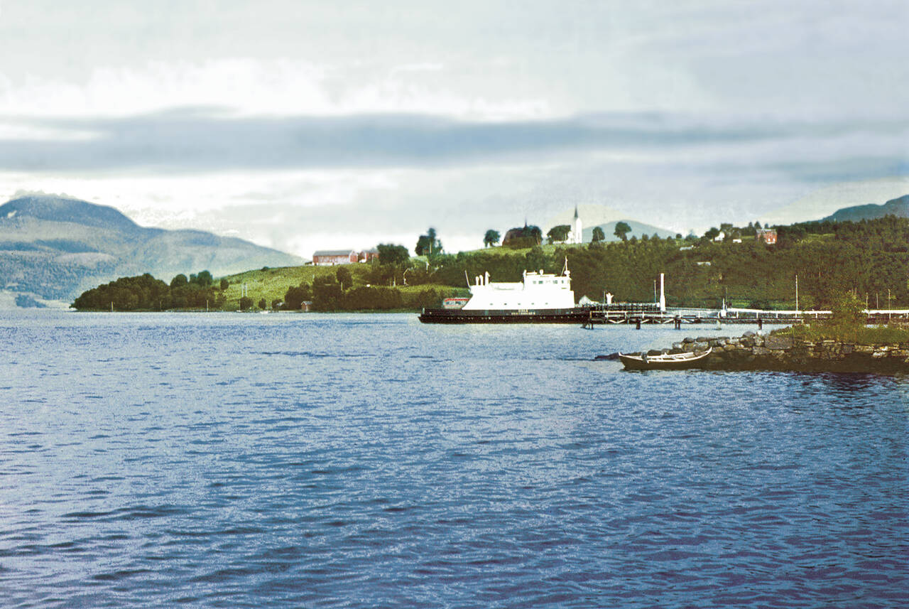 «Gisle» anløper Kvernes rundt 1960. Bak ser vi de historiske kirkene som i dag er en viktig del av Kvernes kulturområde. (Bilde fra boken Med kaffe og svele over fjorden)