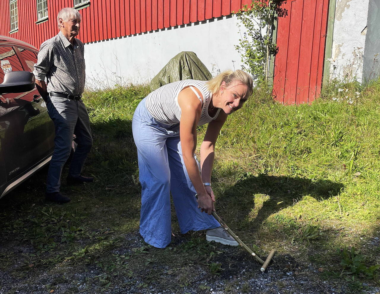 Gjertrud Heggem med «alna», klar til å vippe «jeppen» (kvemsen) som ligg oppå «hullu». Bak: Lars Sjøflot – som dreiv denne sporten for snart 80 år sia. Foto: Bernt Bøe