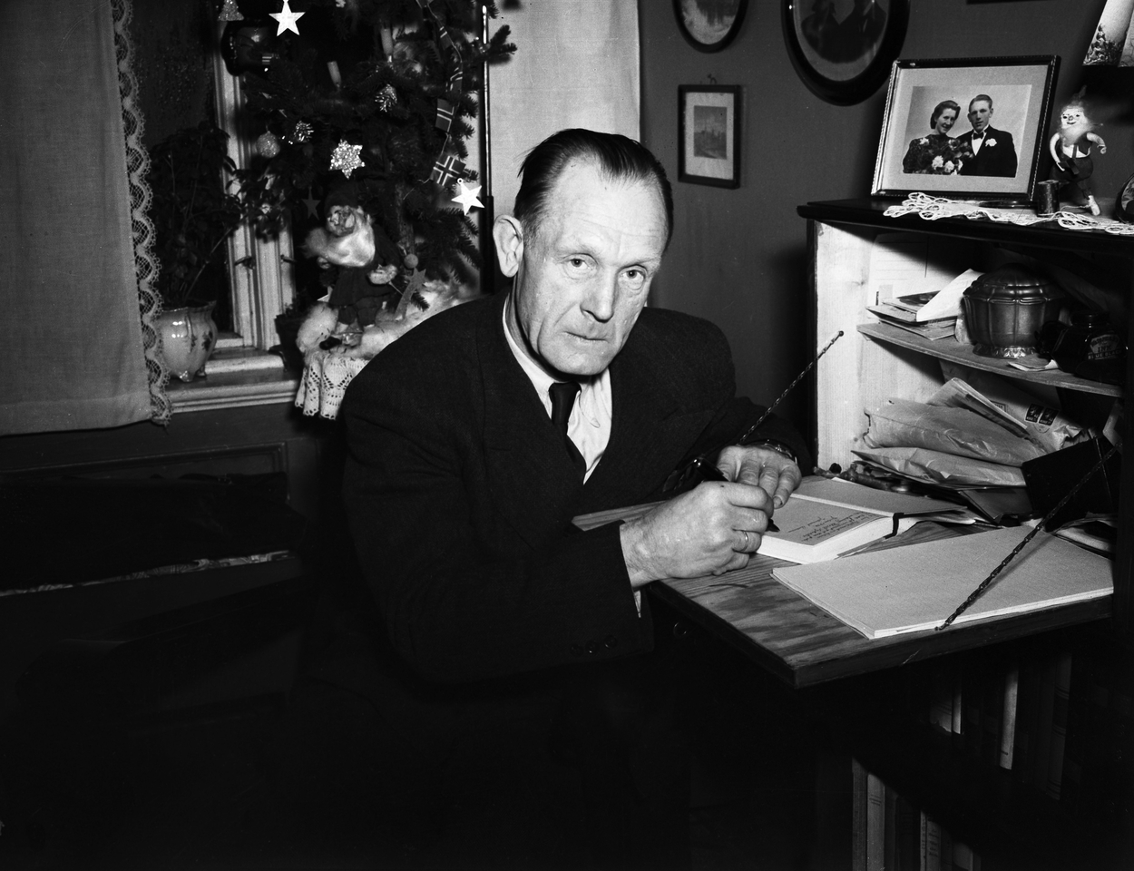 Johannes Sigfred Andersen også kalt "Gulosten" (1898 - 1970) var med i kompani Linge under annen verdenskrig. Her signerer han en bok om sitt liv, 'Vi kommer oss' på bordet foran seg. Foto: TH. Skotaam / Aktuell / NTB- SCANPIX