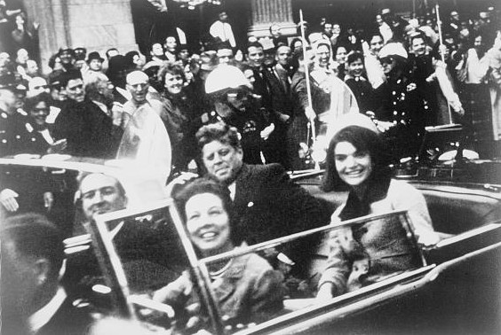 President Kennedy, førstedamen Jacqueline Kennedy, guvernør John Connally og hans kone Nellie Connally i limousinen kort tid før attentatet. By Victor Hugo King, who placed the photograph in the public domain (presumably when he gave it to the Library of Congress). [Public domain], via Wikimedia Commons