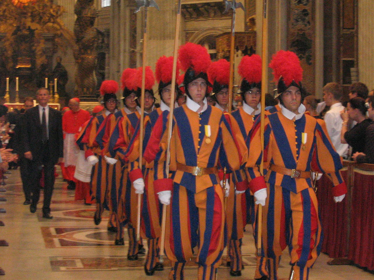 En gruppe paradekledte sveitsergardster i Peterskirken i Italia. Gardistene bærer hellebarder og fjærprydede morionhjelmer, det vil si hjelmer av spansk 1500-talls-modell med brei brem og kam på toppen.By Alberto Luccaroni User:Luccaro (done on my own) [GFDL (http://www.gnu.org/copyleft/fdl.html), CC-BY-SA-3.0 (http://creativecommons.org/licenses/by-sa/3.0/) or CC BY-SA 2.5-2.0-1.0 (https://creativecommons.org/licenses/by-sa/2.5-2.0-1.0)], via Wikimedia Commons