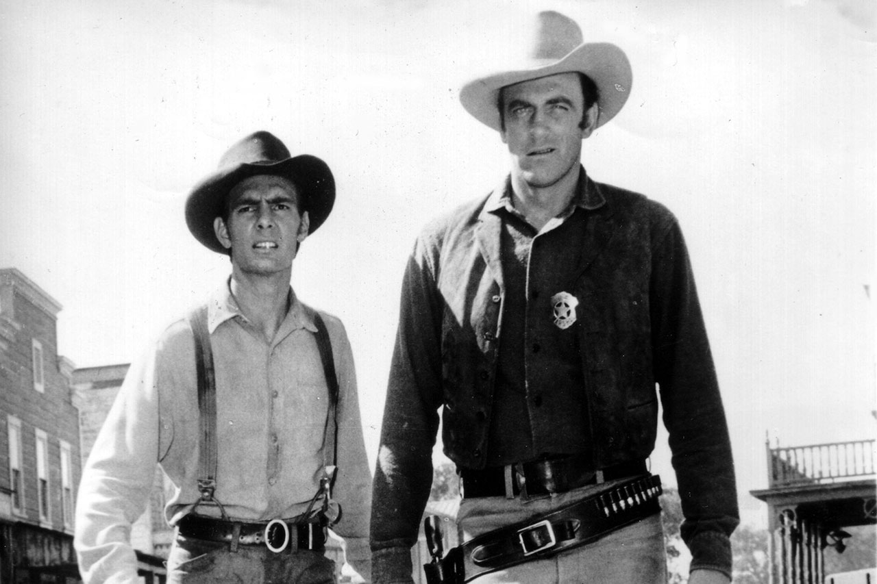Dennis Weaver (t.v) og James Arness fotografert i forbindelse med innspillingen av tv-serien «Gunlaw», 2. juli 1956. Foto: AP Photo
