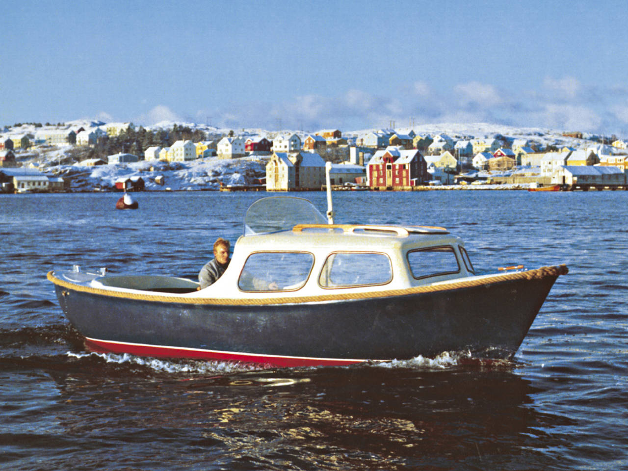 Reklamefoto av Myra 20 snekke på 1960-tallet med deler av Nordlandet i bakgrunnen.