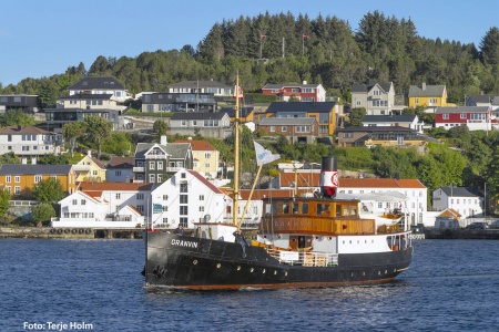 Det historiske lokalruteskipet «Granvin» fra 1931 med de historiske byggene på Innlandet i bakgrunnen. Foto: Terje Holm