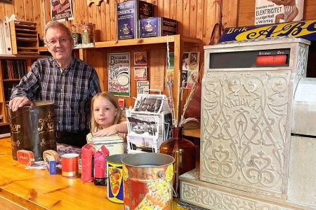 Museet ivaretek mykje utstyr frå butikkane i Bøfjorden, viser Augusta og morfar Bernt ved disken i Litlsalen. Foto: Bandi Bøe