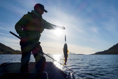 Utførselskvoten tillater i dag turister å ta med seg opp til 18 kilo fiskefilet ut av landet. Bildet viser en mann som fisker i solnedgang på Helgelandskysten. Foto: Gorm Kallestad / NTB
