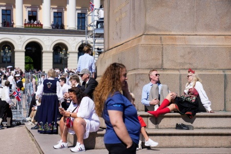 Det er godt og varmt i Oslo fredag. Cecilie Schibstad med røde strømper og Jon Gløersen fra Risør lufter føttene ved Karl Johan-statuen utenfor slottet. Foto: Heiko Junge / NTB