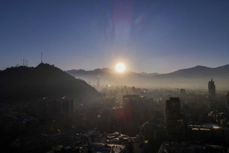 Solen reiser seg over Andesfjellene i Chile med Santiago i forgrunnen. En kraftig geomagnetisk storm er på vei mot jorda etter flere utbrudd fra en stor solflekk. Foto: Esteban Felix / AP / NTB