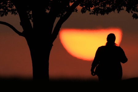 En kvinne kikker på solnedgangen en varm dag i august i fjor i Kansas City i USA. Foto: Charlie Riedel / AP / NTB